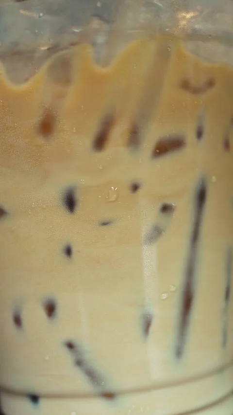 Close Up Iced Latte Coffee Stirred with Straw to Mix Milk and Espresso Stock Footage 332165026
