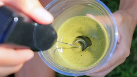 Close-up of iced matcha latte being mixed with handheld frother in plastic cup Stock Footage 315855462