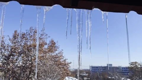 Close-Up Icicles Above Window With Winter Sky and City Background Stock Footage 336841238