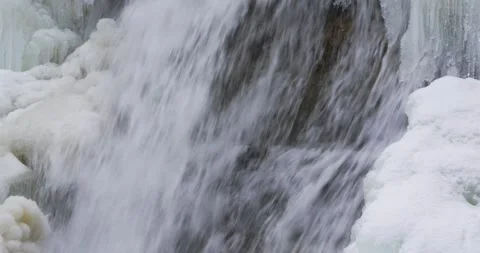 Close up of an icy waterfall, river, flowing with snow and ice along each side. Stock Footage 297627532