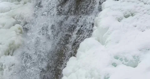 Close up of a icy waterfall, river, flowing with snow and ice along each side. Stock Footage 297637367