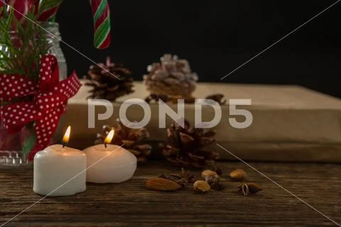 Close up of illuminated candles with pine cones and gift box Stock Photos