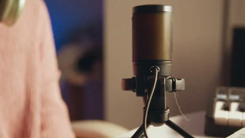 Close-up of illuminated microphone and hand interaction on desk tripod in warm Stock Footage 345655673