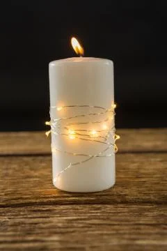 Close up of illuminated string lights wrapped on lit candle Stock Photos