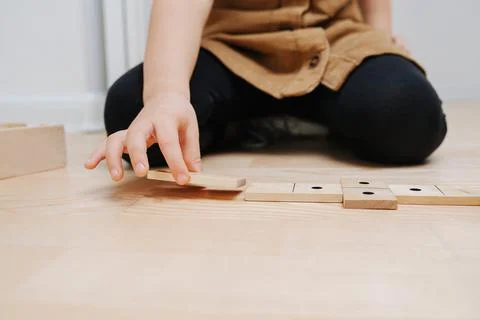 Close up image of a boy sitting on the floor, playing with domino pieces Stock Photos
