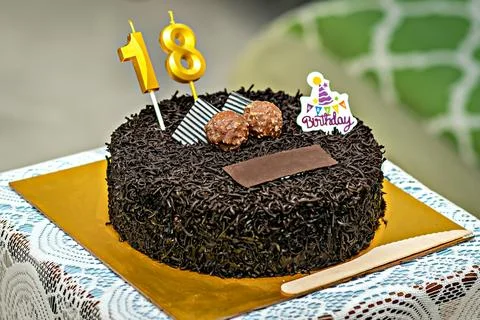 Close up image of a brown textured cake with golden letters of 18 and some .. Foto stock