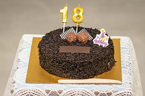 Close up image of a brown textured cake with golden letters of 18 and some .. Stock Photos