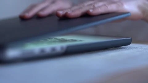 A close-up image capturing a person's hand closing a dark-colored laptop Stock Footage 264981003