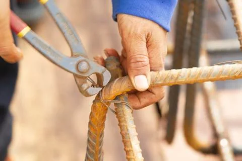 Close up image of construction worker securing steel bars with wire rod for r Stock Photos