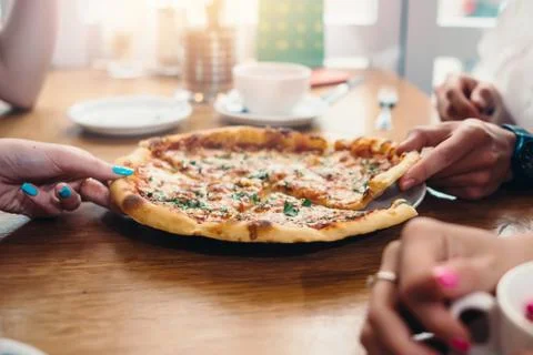 Close-up image of delicious pizza and hands taking slices in Italian restaurant Stock Photos
