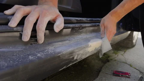 Close-up image of the dusty and dirty hands of a man manually sanding a car part Stock Footage 278035957