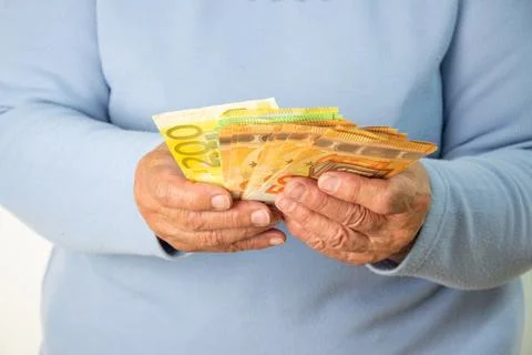 A close-up image of an elderly persons hands holding a stack of Euro banknote Stock Photos