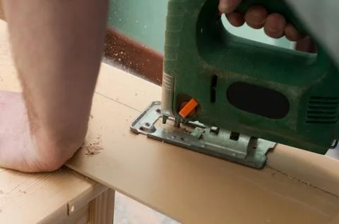 Close up image of an electric jigsaw cutting sheets on a wooden plank Fotos Stock