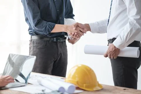 Close-up image of an engineer shaking hands with his coworker during the meeting Stock Photos