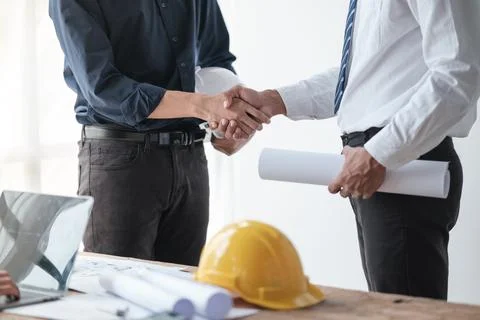 Close-up image of an engineer shaking hands with his coworker during the meeting Stock Photos