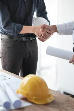 Close-up image of an engineer shaking hands with his coworker during the meeting Stock Photos