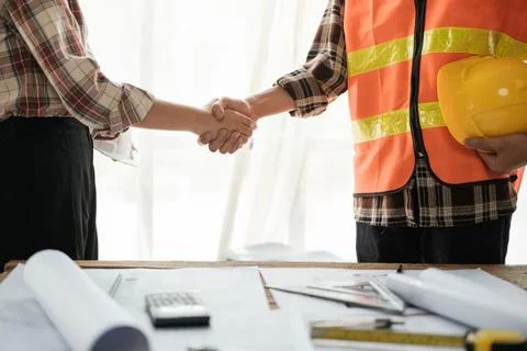 Close-up image of an engineer shaking hands with his coworker during the meeting Stock Photos
