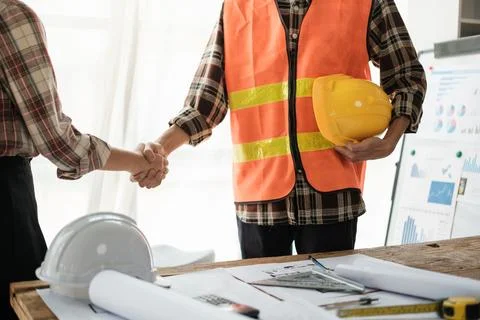 Close-up image of an engineer shaking hands with his coworker during the meeting Stock Photos