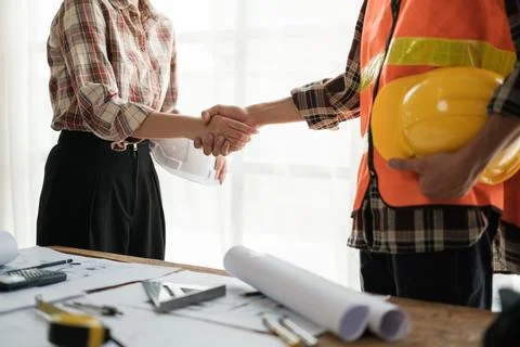 Close-up image of an engineer shaking hands with his coworker during the meeting Stock Photos