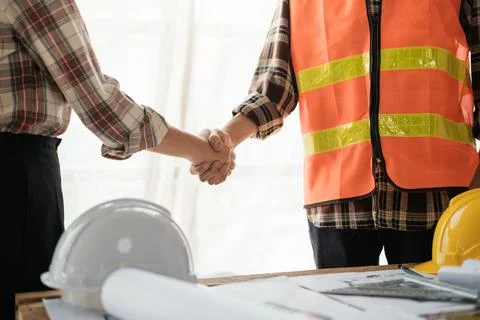 Close-up image of an engineer shaking hands with his coworker during the meeting Stock Photos