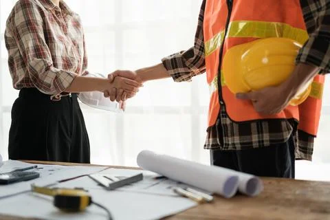 Close-up image of an engineer shaking hands with his coworker during the meeting Stock Photos