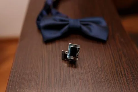 A close-up image featuring a dark navy blue bow tie and a silver lapel pin re Stock Photos