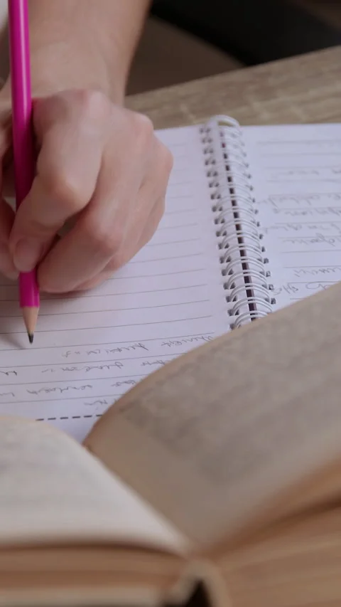 Close-up image of a female student studying and summarizing information from a Stock Footage 305408093