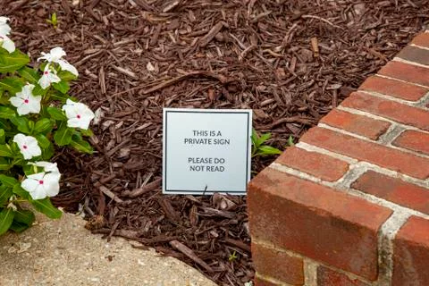 Close up image of a funny and creative yard sign placed among wood chips Stock Photos