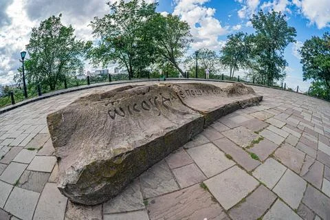 Close-up image of a gray-brown boulder with engraved text, in a park or rec.. Stock Photos