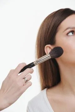 Close up image of a hand applying setting powder to a woman's face Stock Photos