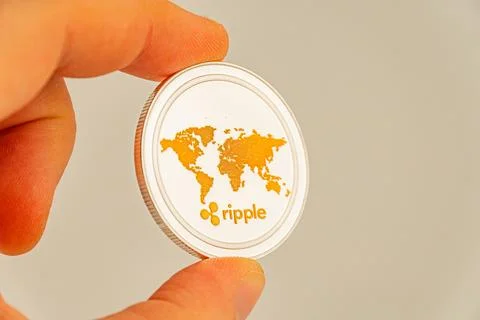 A close-up image of a hand holding a globally themed logo-embossed token or.. Stock Photos