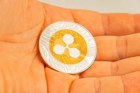 Close-up image of a hand holding a physical Tether coin token, featuring th.. Stock Photos