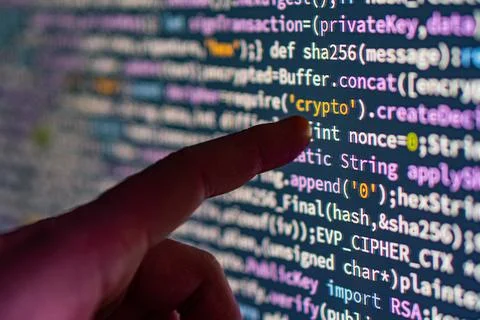 Close-up image of a hand pointing at computer code on a screen related to c.. 스톡 사진