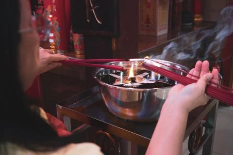 Close-up image of hands lighting red incense in a traditional Chinese temple Stock Photos
