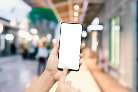 Close-up image of hands using smartphone in evening on city shopping street, Photos