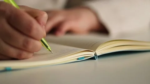 Close up image of human holding pen and writing something on blank white page Stock Footage 310605274