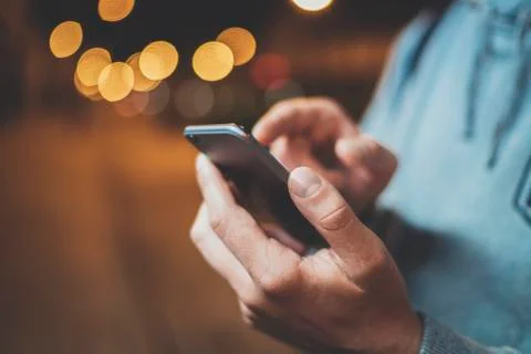 Close-up image of male hands using modern smartphone at night Stock Photos