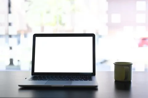 Close up image of mock up laptop computer and coffee cup on white table. Stock Photos