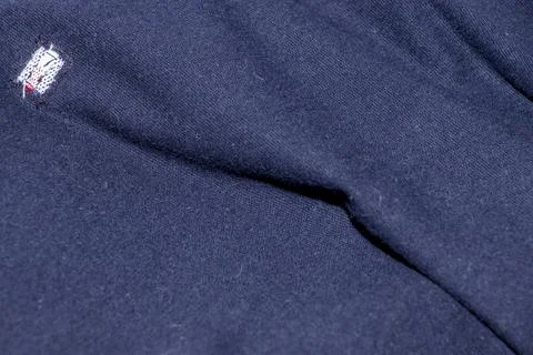 Close-up image of a navy blue fabric featuring a small logo. The texture Stock Photos