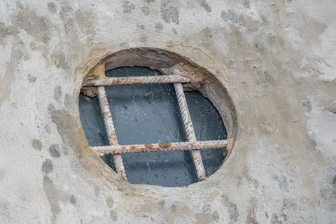 Close-up image of an old, weathered round window with vertical bars on a disc Foto stock