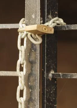 Close up image of a padlock closing a barred door Stock Photos