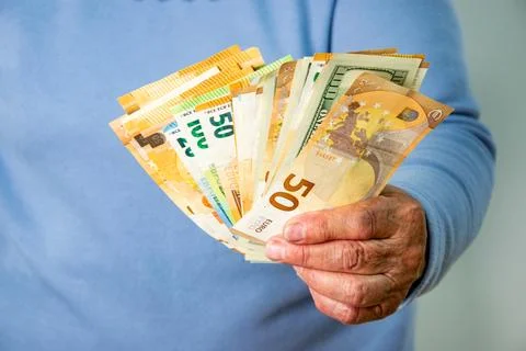 Close-up image of a persons hand holding a fan of Euro and Dollar banknotes Stock Photos