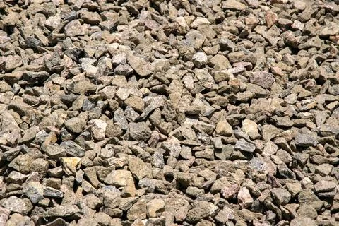 A close-up image of a pile of small, tan and gray gravel stones, illuminate.. Stock Photos