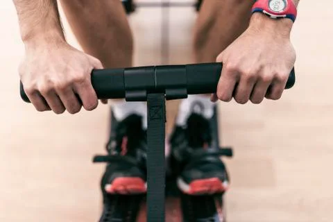 Close-up image of rowing athlete hands in gym exercise machine Stock Photos