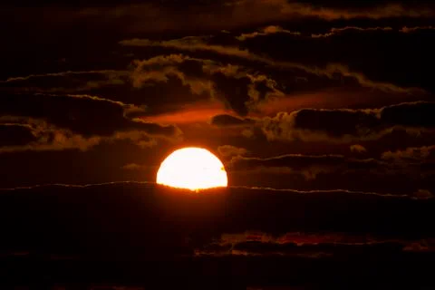 Close up image of the setting sun among the clouds. Stock Photos