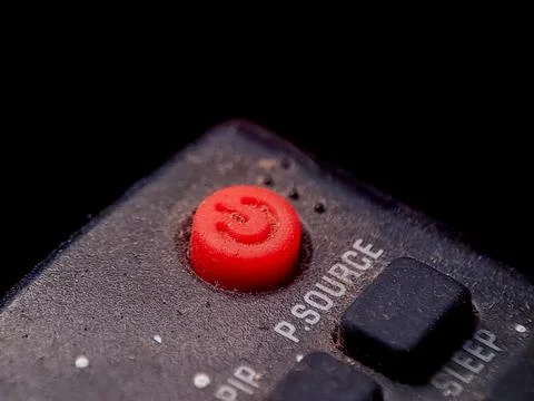 Close up image showing a red power button on a remote with a rough textured.. 写真素材