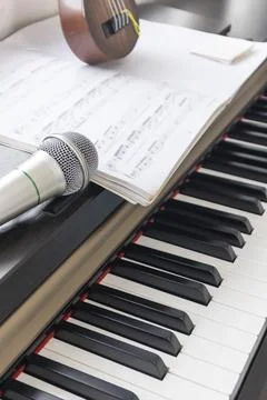 The close-up image shows a microphone placed on a piano with sheet music op.. Stock Photos