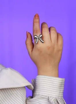 Close-up image of silver ring shaped like a bow on female hand Stock Photos