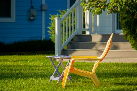 Close up image of a  simple yellow plastic chair and a foldable table Stock Photos