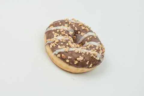 A close-up image of a single chocolate-glazed, nut-sprinkled donut resting on Stock Photos